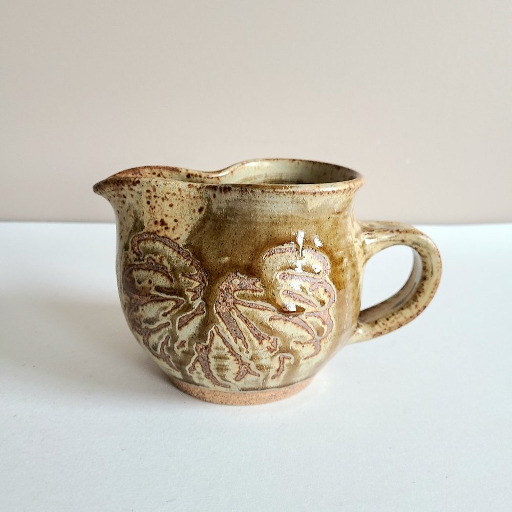 Hand made pottery. Stoneware pitcher with floral design. Signed by artist.